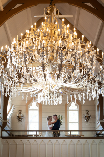 Bride, groom under a magnificent chandelier.